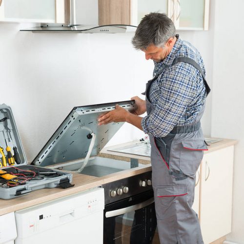 Photo Of mature repairman examining stove in kitchen